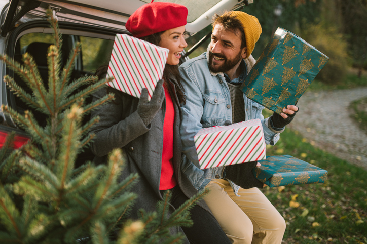 Couple sharing Christmas presents, sitting in car boot.